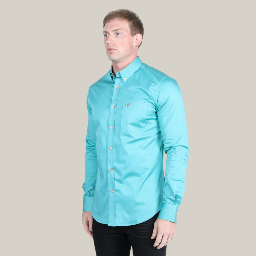 A man in a Men’s Single Pocket Logo Modern Fit Stretch Dress Shirt - Turquoise (CTL9829) and black pants stands against a plain beige background, slightly facing left with a neutral expression.