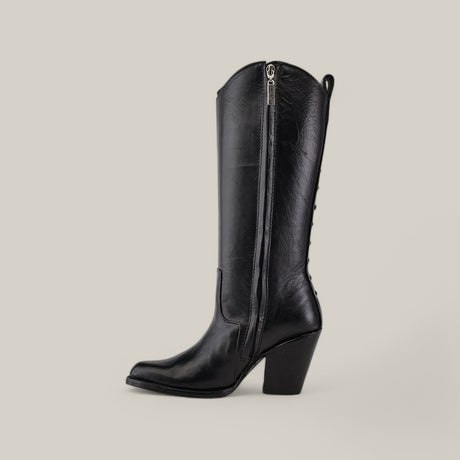 Set against a beige backdrop, the chic black leather cowboy boot from the Platinum Collection boasts a side zipper and mid-height chunky heel. Its slightly pointed toe and subtle shine make it as stylish as the Francia Rings Tall Shaft Black - J Toe Boot.