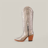 Introducing the Linda Tall Shaft Mercury - J Toe from the Platinum Collection, featuring metallic silver cowboy boots with intricate swirl patterns, a mid-height wooden heel, and a side zipper. Displayed against a light background, these boots are an essential addition to any stylish ensemble.