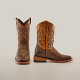 The Azkar Tan Square Toe boots, handcrafted from brown cowhide leather, feature intricate embroidery and stitching, square toes, and stacked heels. Positioned against a plain white background, both a side and front view are showcased.