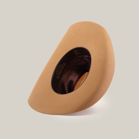 The 6X Leandro Fawn, a tan felt hat made from premium sheeps wool, is displayed on its side to showcase its dark brown interior against a plain white background.