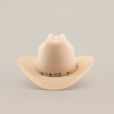 The 6X 2 Carnales Bone is a cream-colored felt hat with a wide brim and a decorative band featuring small conchos encircling the crown, set against a plain white background.