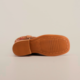 The image presents the bottom view of the Mia Copper Suede - Square Toe shoe in brown, highlighting its grooved sole on a white background. The sole has a textured pattern, and the upper section displays embroidery reflecting premium leather craftsmanship.