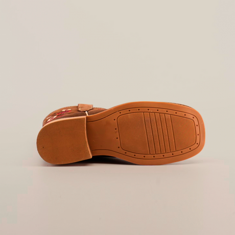 The image presents the bottom view of the Mia Copper Suede - Square Toe shoe in brown, highlighting its grooved sole on a white background. The sole has a textured pattern, and the upper section displays embroidery reflecting premium leather craftsmanship.