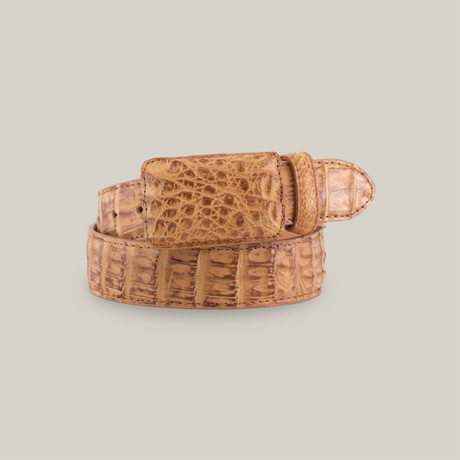 The Exotic Full Quilt Caiman - Antique is a brown leather belt with a rectangular buckle, featuring an antique-finished crocodile pattern, highlighting the scales and details. Its coiled with the buckle facing forward.