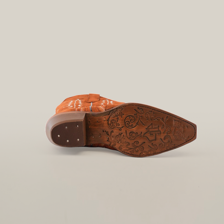 The image features the sole of a Caroly Brick Suede Boot, made from premium leather with floral patterns. Positioned on a plain white background, the boots toe points to the top right. The sole is brown, paired with a light brown heel.