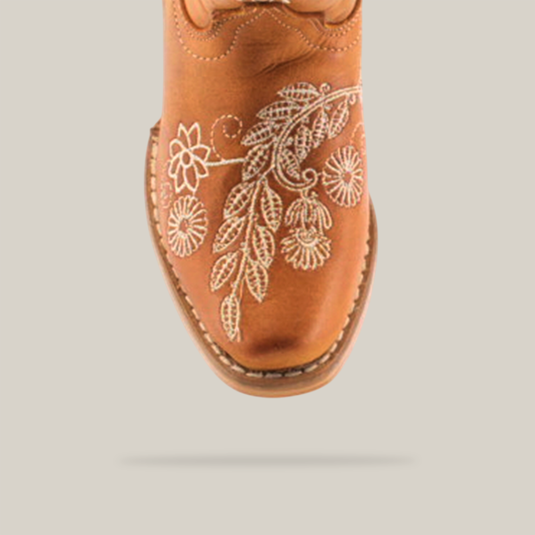 The Rama Honey - Snip Toe boots feature genuine leather in a brown cowboy style for young girls. White floral embroidery enhances the toe, complemented by stitched leaf and flower patterns for a classic textured design.