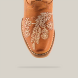 The Rama Honey - Snip Toe boots feature genuine leather in a brown cowboy style for young girls. White floral embroidery enhances the toe, complemented by stitched leaf and flower patterns for a classic textured design.