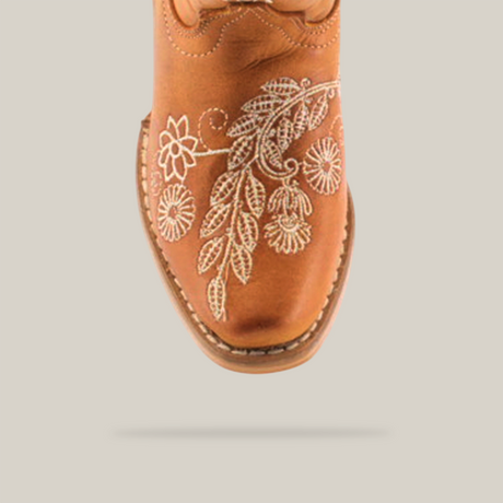 The Rama Honey - Snip Toe boots feature genuine leather in a brown cowboy style for young girls. White floral embroidery enhances the toe, complemented by stitched leaf and flower patterns for a classic textured design.