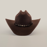 The 6X Country Brown is a Western classic felt cowboy hat made from premium sheep wool. It has a wide brim, pointed crown, and is adorned with a decorative black band featuring silver star accents on a plain white background.