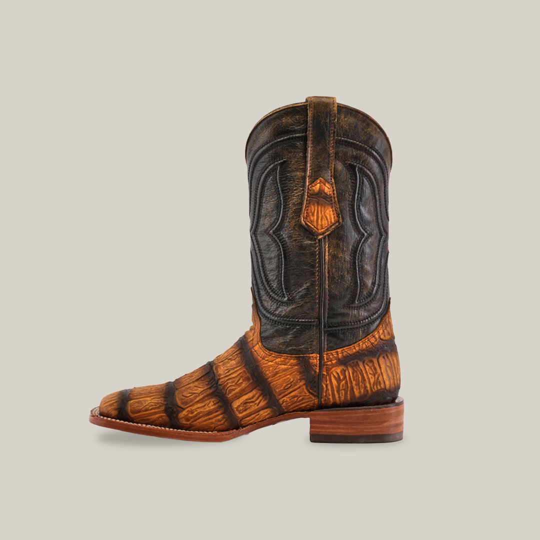 The Gator Print Rustic Honey - Square Toe boot displays a dark upper and textured striped brown lower, made from premium cowhide leather. It features intricate shaft stitching and a low heel, set against a plain white background.