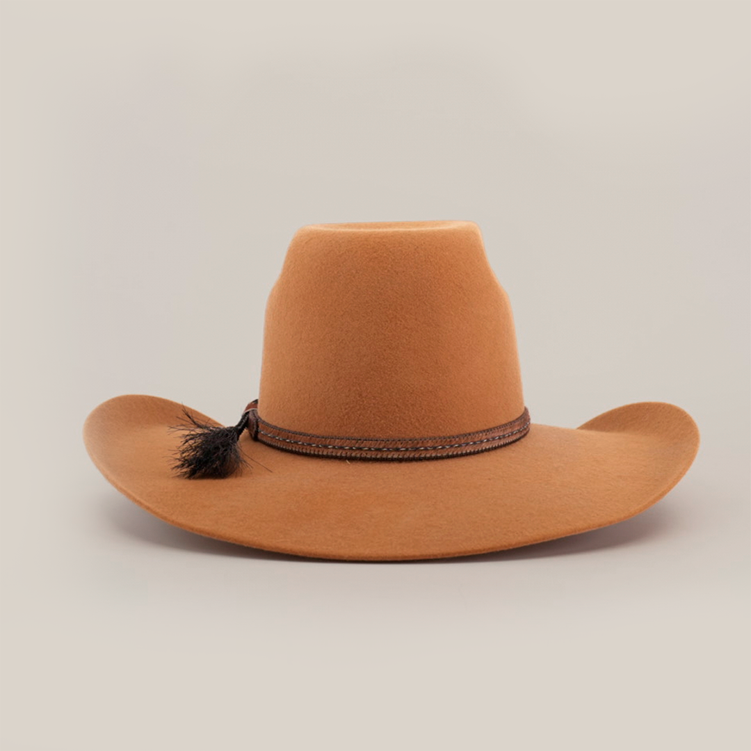 The 6X Brazil Fawn is a brown cowboy hat featuring a flat brim and decorative braided band with a small tassel on the right side, crafted from premium leather, and displayed against a white background.