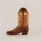 The Western Stitch Camel features premium leather in a single brown short shaft boot with detailed stitching, a unique heart-shaped cutout near the top, and is presented against a white background. This luxury western piece boasts a narrow square toe and sturdy heel.