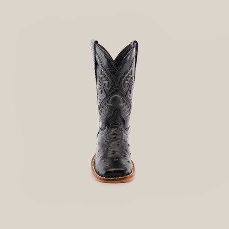 The Karoo Ostrich Print Black Square Toe boot, made from premium cowhide leather, showcases intricate stitched patterns and features a distinct square toe with a brown sole. It stands against a plain white background, reflecting timeless elegance and quality craftsmanship.