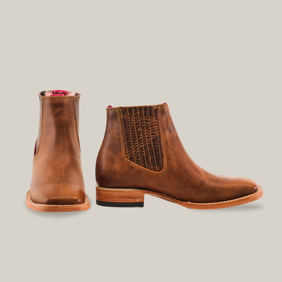 Two Avejentado Honey square toe leather ankle boots are shown, one facing forward and the other in profile. Featuring elastic side panels with texture, a wooden sole, and contrasting red lining for flair—perfect for any relaxed cowboy look.