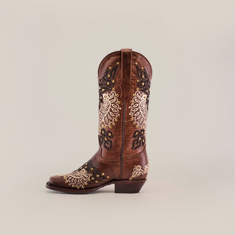 The Faenza Crystals Brown cowboy boot, with a mid shaft and narrow square toe, features ornate white and black embroidery with gold studs on a plain white background, offering timeless elegance.