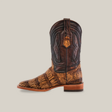 The Gator Print Orix - Square Toe is a handcrafted cowboy boot, showcasing a textured, dark brown cowhide leather upper with intricate stitching and a lighter Gator Print Orix design on the foot and lower shaft, completed by a wooden heel against a plain white background.