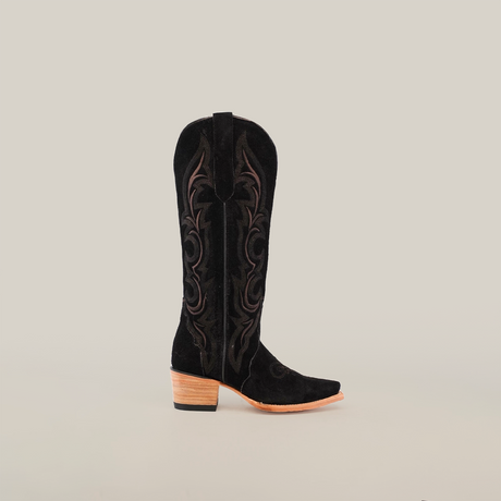 The Amara Black Suede - Tall Shaft - Snip Toe cowboy boot features intricate brown embroidery, a snip toe, and a wooden stacked heel. Its design is striking against the plain white background.