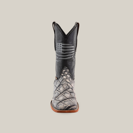 The American Alligator Print Rustic Black boot, with a black shaft featuring an American flag design, sports a textured alligator print on the foot. It boasts a light brown sole and square toe, all against a plain white background.