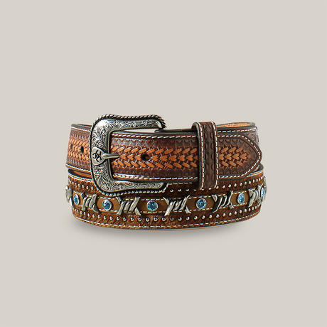 The Ariat Mens Brown Barbed Wire and Calf Hair Western Belt - A1027202 showcases rugged elegance with its detailed silver buckle, intricate woven pattern, and decorative light blue studs against a white background, nodding to Western heritage.