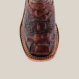 The Alligator Head Print Rustic Honey Square Toe cowboy boot features a scaly pattern with intricate stitching, crafted from premium brown leather. Its square toe design and light-colored sole highlight its western fashion and handcrafted allure.