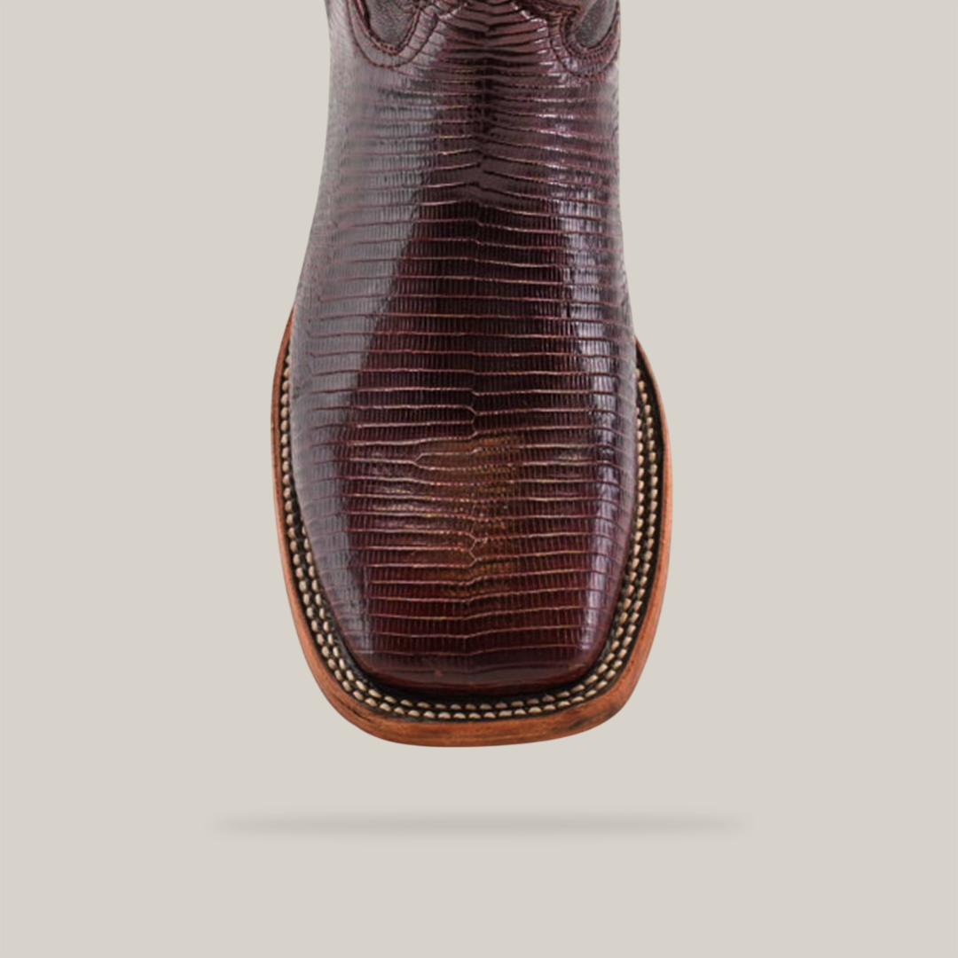 The Exotic Lizard - Brown - Square Toe cowboy boot showcases a textured design with a genuine lizard leather finish and intricate stitching. Its smooth surface contrasts beautifully against a light-colored backdrop.