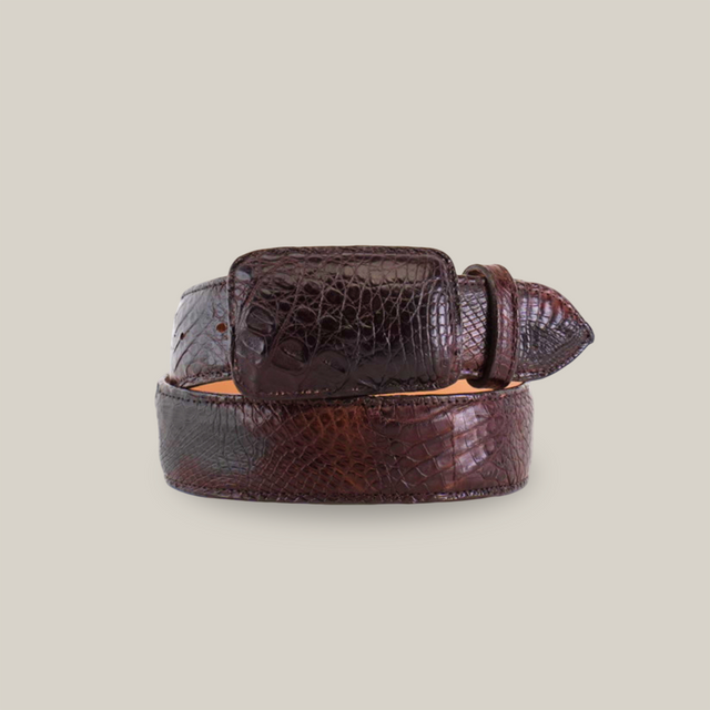 The Exotic Full Quilt Caiman - Brown Belt, with its crocodile texture and glossy finish, has a neatly coiled design resembling genuine caiman skin. It features a rectangular buckle and pointed end, beautifully showcasing the detailed pattern.