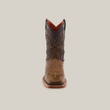 The Ranch Camel Square Toe is a single brown cowboy boot made from cowhide leather, featuring intricate stitching and a slightly pointed toe, displayed upright against a white background. It captures western elegance with a darker upper section adorned with detailed patterns.