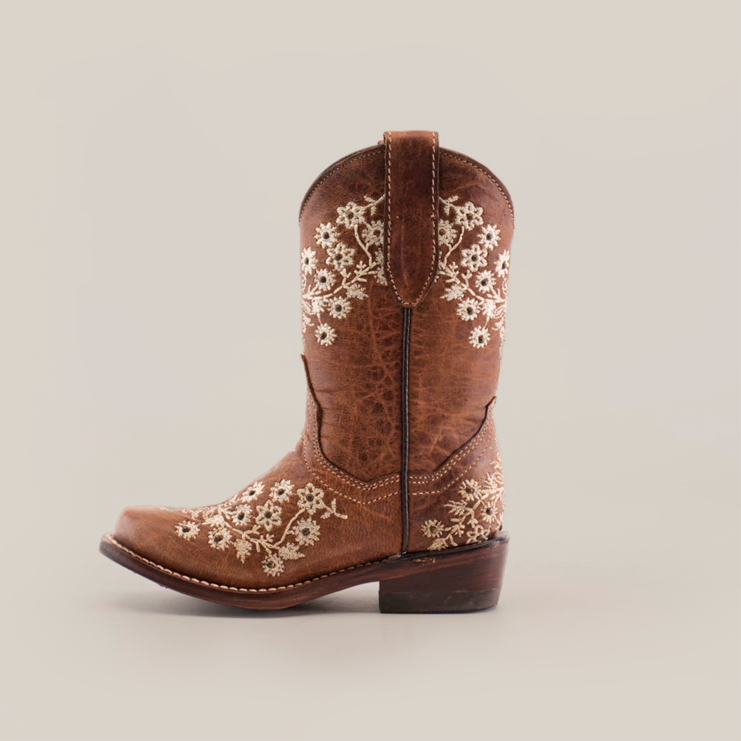 A single Abril Studs Orix Snip Toe cowboy boot in brown, featuring intricate white floral embroidery on the shaft and foot, showcased against a white background. This snip toe boot has a wooden heel and includes pull tabs for easy wear.