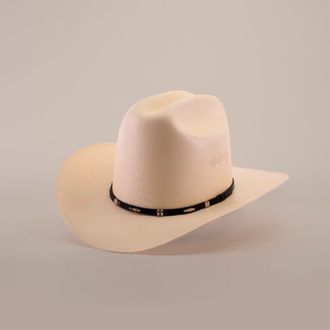 The 500X Dos Carnales Straw Hat, renowned for its quality and durability, boasts a wide brim with a black band at the base. Positioned perfectly on a plain, soft backdrop, this light cream-colored cowboy hat exemplifies style and function.