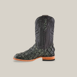 The Exotic Piraruco Fish - Charcoal is a single cowboy boot featuring a dark green and black reptile pattern from Piraruco fish leather on the foot and a smooth black leather shaft with intricate stitching. It has a wooden heel, light-colored sole, and distinct square toe design for fashion enthusiasts.