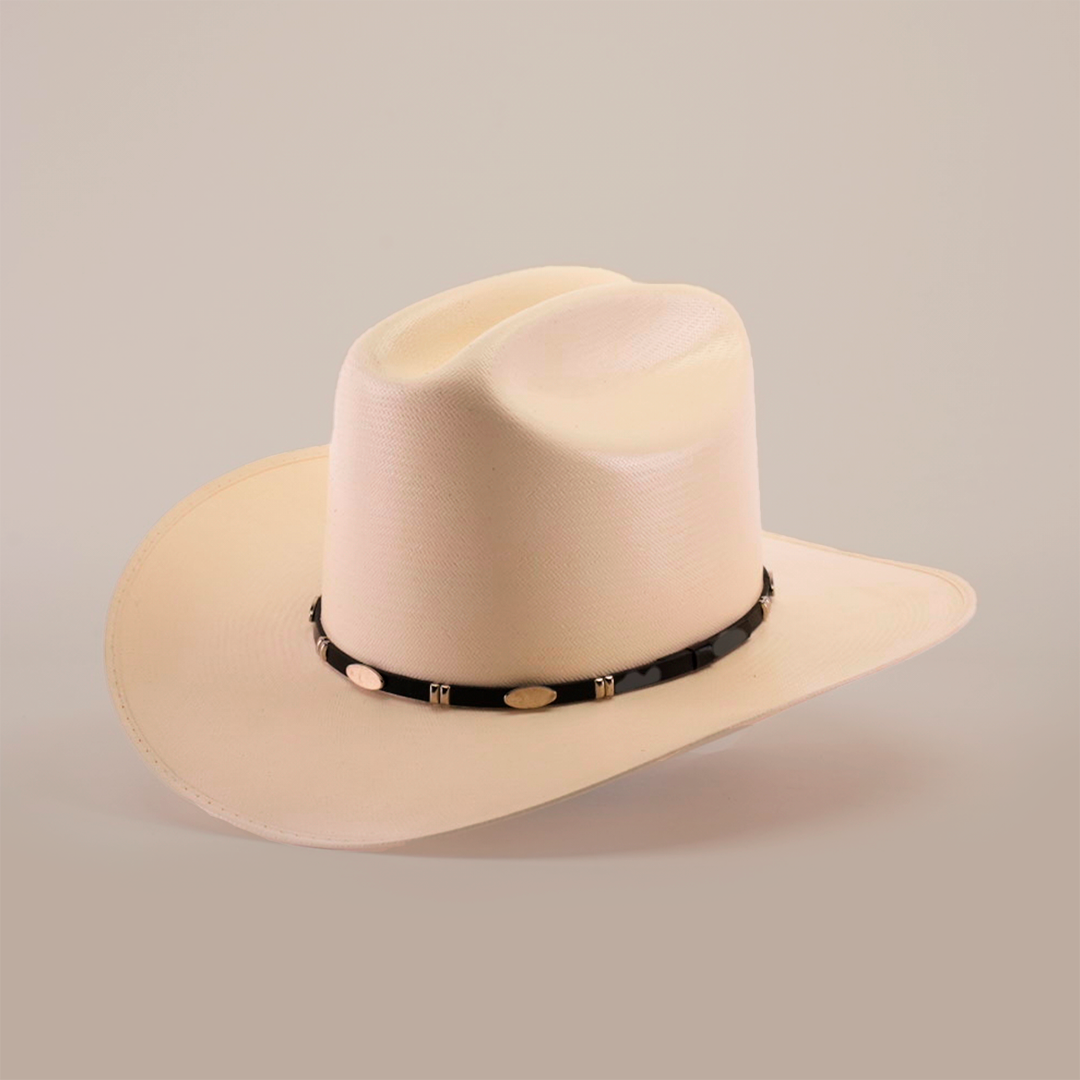 The 1000X Dos Carnales Straw Hat is a beige cowboy hat with a wide, curved brim and a black band featuring light decorative elements. Its exceptional quality and craftsmanship are highlighted against a plain background, making it an iconic accessory.