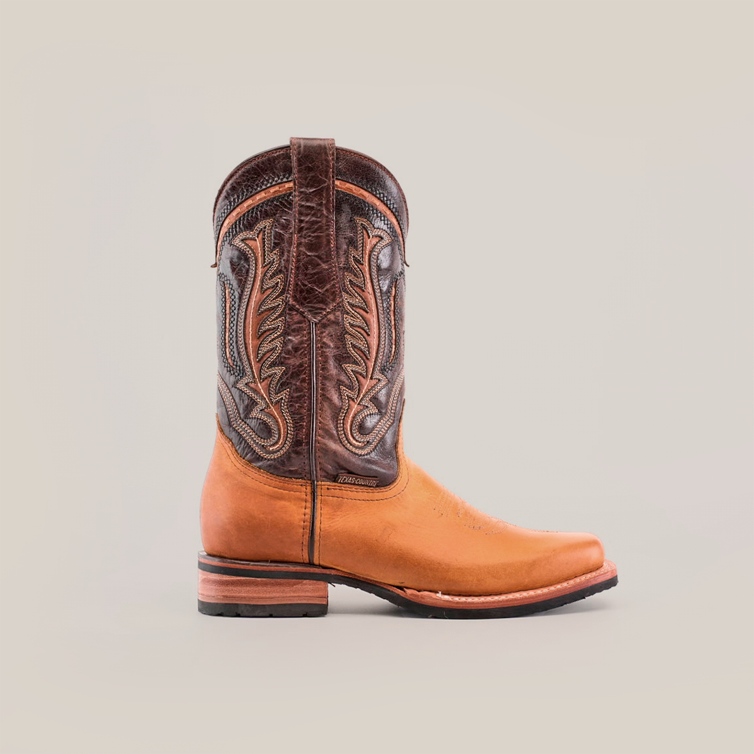 The Cater Honey boots, crafted from premium cowhide leather in rich brown and tan, feature an ornate-stitch design. With a rodeo toe, wooden heel, and slip-resistant sole, they perfectly blend style and function.