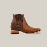 The Avejentado Honey Square Toe boasts a side view of an elegant and rugged brown leather Chelsea boot, featuring cowboy-style elastic panels, textured pattern, wooden sole, low stacked heel, and a small top tag against a white background.