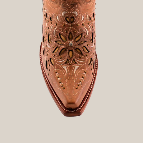 Close-up of a brown leather cowboy boots toe, showcasing detailed floral cut-out designs and decorative stitching. Made from premium leather with a pointed tip and visible seams, it mirrors the elegance of Kiara Crystals Fawn Mid Shaft Snip Toe boots.