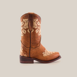 The Martey Crystals Sahara - Snip Toe is a brown cowboy boot adorned with detailed white floral embroidery and crystal embellishments on the shaft and toe, seen from the side. It has a low heel and a rounded toe.