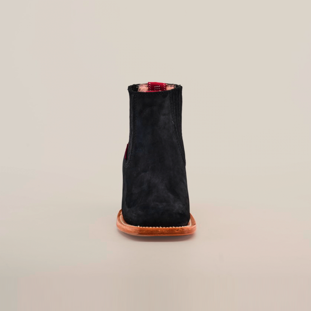 The Prime Suede Black Square Toe, a black suede ankle boot with a cowboy flair featuring a square toe and brown leather sole, is photographed from the front against a plain white background.