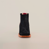 The Prime Suede Black Square Toe, a black suede ankle boot with a cowboy flair featuring a square toe and brown leather sole, is photographed from the front against a plain white background.