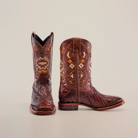 The Exotic American Alligator Patchwork Brown Square Toe boot is depicted on a white background, showcasing intricate geometric and arrow embroidery. It features a rugged texture and low heel, crafted from genuine alligator skin for an exotic appeal.