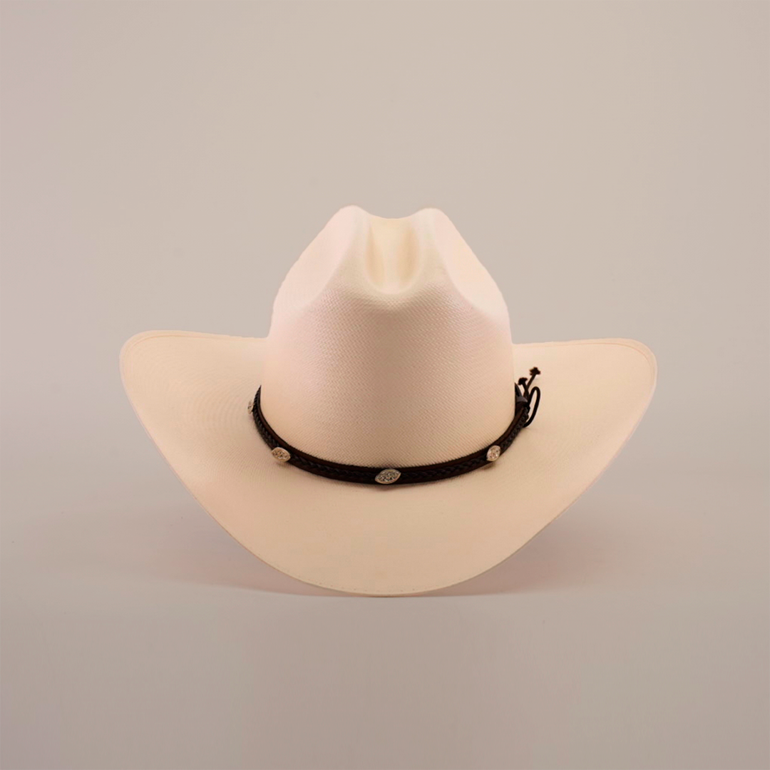 The 1000X Sinaloa Straw Hat features an elegant design with a wide brim, a black band adorned with silver conchos, and a plain white background.