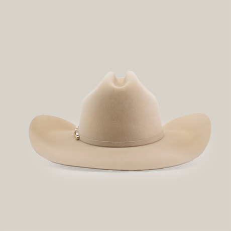 The 100X Tony Lama Belly is a beige cowboy hat made from premium beaver fur, showcasing a wide brim and top crease, with a small metallic emblem on one side. It exudes genuine Western elegance against a plain white background.