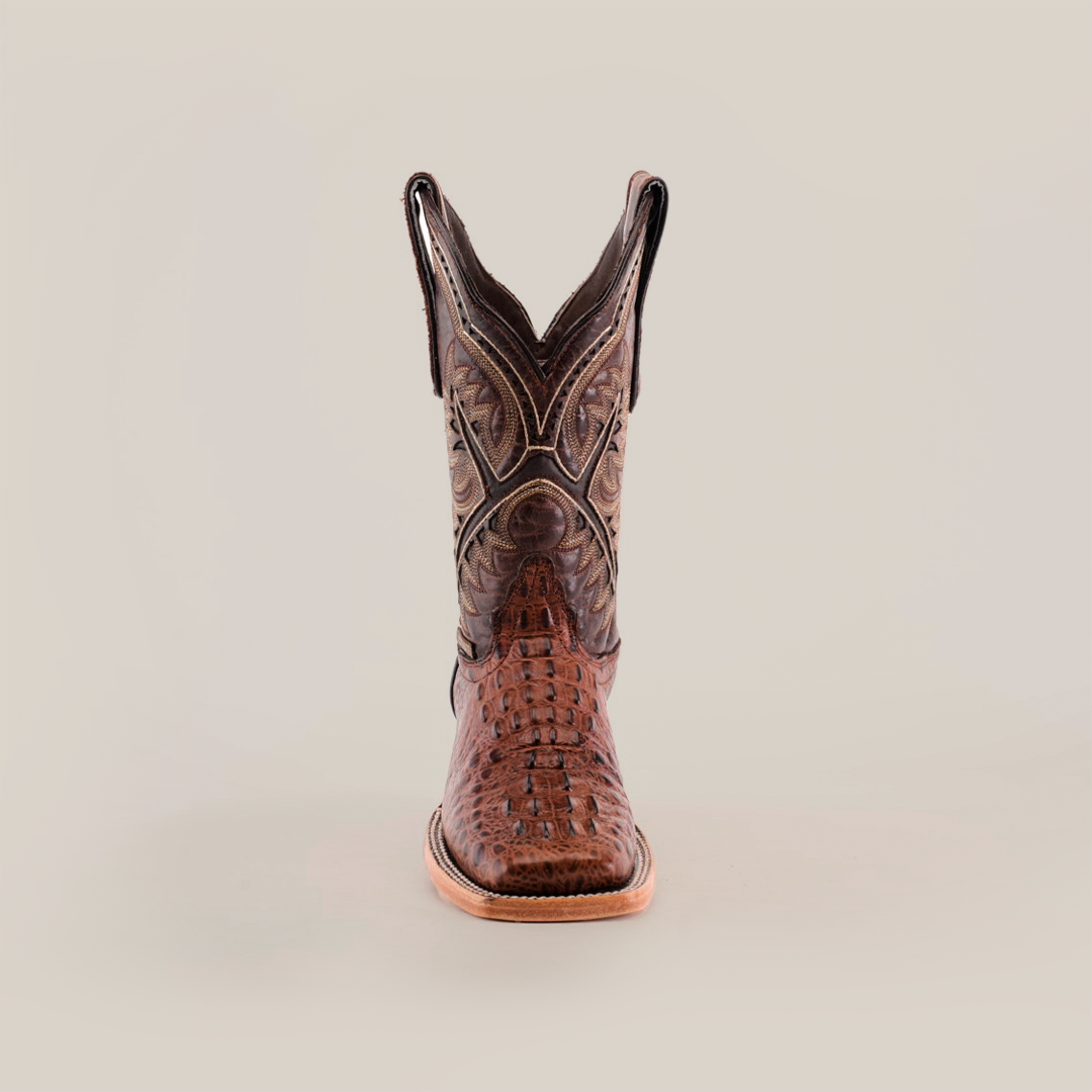 Front view of a single luxury boot, named Caiman Hornback Print Chocolate Square Toe, crafted in brown caiman hornback print with intricate stitching and a pointed toe, set against a pristine white background.