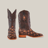 A pair of Big Bass Pirarucu Print Rustic Brown - Square Toe cowboy boots features an intricate design. One boot stands upright, and the other tilts slightly, highlighting its side detail and wooden heel against a plain white background.