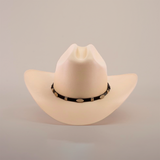 The 5000x Sinaloa Straw Hat, in cream, exudes elegance with its wide brim and a black hatband adorned with oval decorative elements, highlighting fine craftsmanship against a plain white background.