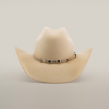 The 6X Chihuahua Bone, a light beige Western hat made from premium sheep wool, boasts a wide brim and a decorated band with metallic accents around the crown, standing out stylishly against a plain white background.