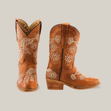 The Rama Honey - Snip Toe boots, crafted from genuine leather, feature beige floral embroidery. These brown cowboy boots have a wooden heel with intricate flower and leaf designs. One boot is forward-facing while the other is turned to the side, perfect for little girls footwear.