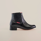 Introducing the Napa Black Square Toe, a modern wardrobe staple. This handcrafted black leather ankle boot showcases elastic side panels, a low heel, and subtle red stitching near the top edge, all set on a plain white background.