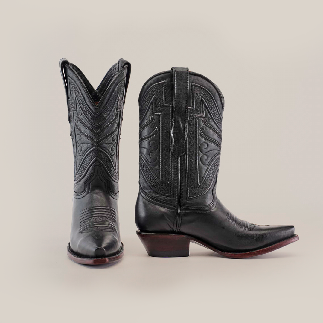 The Plane Jane Black- Short Shaft - Snip Toe boots, with premium leather and intricate shaft stitching, embody Western artistry. One boot stands upright showing its detailed side; the other points forward against a plain white background.