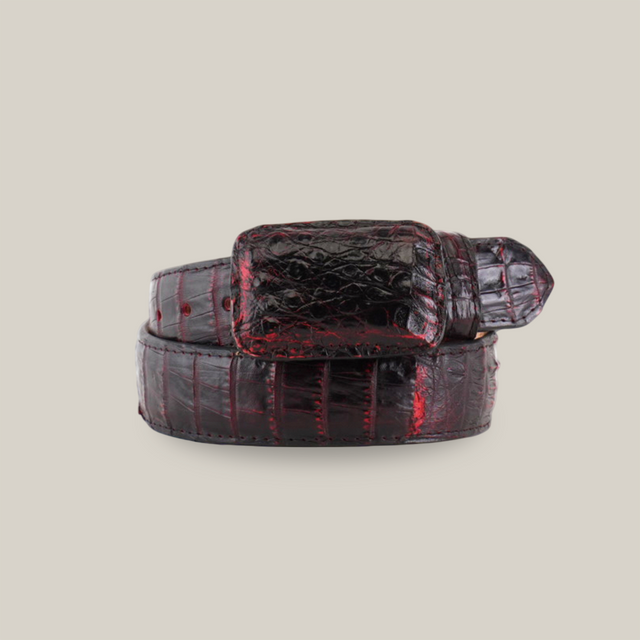 The Exotic Full Quilt Caiman - Black Cherry Belt is a luxurious dark red and black belt with a shiny finish, neatly rolled. It features a squared buckle that highlights the detailed texture and pattern of genuine crocodilian leather.