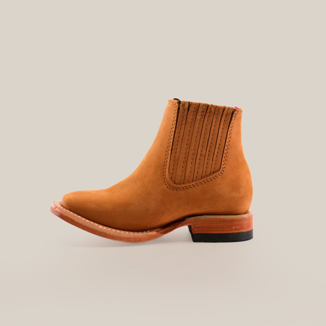 The Prime Suede Honey Square Toe boot is a single brown suede ankle boot with a square toe, elastic side panel, and wooden heel, showcased against a plain white background.